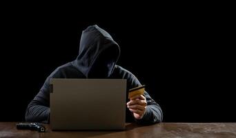 Hacker spy man one person in black hoodie sitting on table looking computer laptop used login password attack security to data digital internet network system night dark background copy space photo