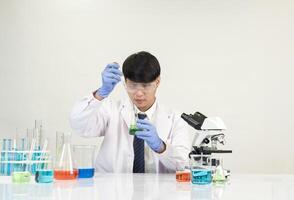 Man asian student education learning scientist wearing doctor gown in lab looking hand at chemist. caused by mixing reagents in scientific research laboratories with test tubes and microscope on table photo