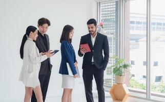 Business man and woman asian group team standing smile cheerful talk looking holding tablet and hands up happy with in agreement ready new project job for work in room office company white background photo