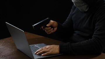 Portrait hacker spy man one person in black hoodie sitting on table looking computer laptop used login password attack security to data digital internet network system night dark background copy space photo