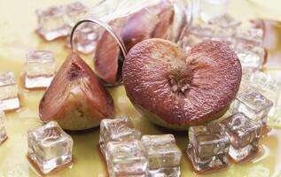 Blurred of Plumcot fruit with red and juicy pulp wet from red wine and ice cubes, photo