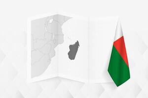 A grayscale map of Madagascar with a hanging Madagascan flag on one side. Map for many types of news. vector