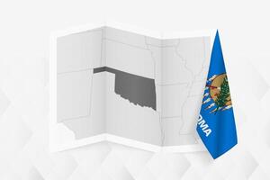 A grayscale map of Oklahoma with a hanging Oklahoma flag on one side. Map for many types of news. vector