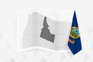 A grayscale map of Idaho with a hanging Idaho flag on one side. Map for many types of news. vector
