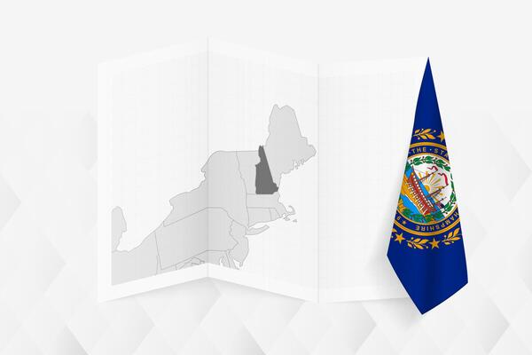 A grayscale map of New Hampshire with a hanging New Hampshire flag on one side. Map for many types of news.