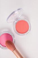 Two transparent round packs of dry decorative blush of different tones on a white background. a brush for applying makeup. The top vertical view. photo