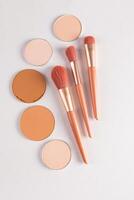 Beautiful beige makeup brushes and some round blocks, a refill of various tones on a white background. The top vertical view. flat lay. Decorative. photo