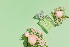 A unbranded perfume bottle on a light green delicate background with a small roses and gypsophila. The top view . a copy space. A blank bottle mockup. photo
