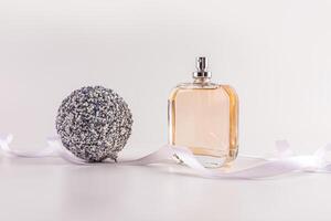 Classic unbranded perfume bottle on a white background with a silver ball and a white ribbon. Front view. Bottle layout. Fragrance presentation. photo