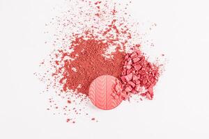 round block, refill blush with a relief pattern of pink tone and a scattering of dry blush on a white background. texture, a sample of blush. top view photo