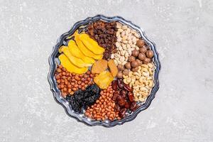 A large silver dish with a dried fruits and nuts on a gray cement background. top view. A copy space. The concept of the Tu Be Shvat . healthy food. photo