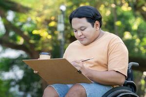 Young Artist in Wheelchair Sketching Outdoors in a Park on a Sunny Day with Coffee photo