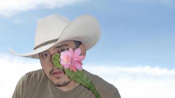 Man with cowboy hat holds cactus flower against clear blue sky background photo