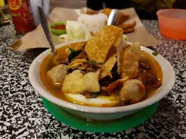 A bowl of soup with a spoon and a plate of food photo