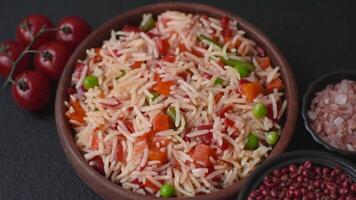 Boiled rice with vegetables, salt and spices on a dark concrete background video