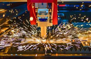 Industrial laser cut machine while cutting the sheet metal with the sparking light. photo