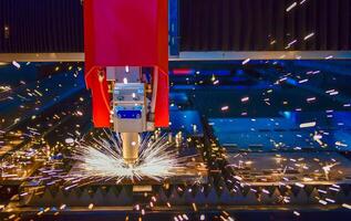Industrial laser cut machine while cutting the sheet metal with the sparking light. photo