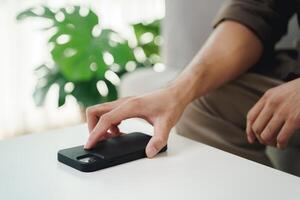 Close up of a man's hand is to put his mobile phone on the table after stopping using it. photo