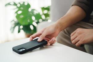 Close up of a man's hand is to put his mobile phone on the table after stopping using it. photo
