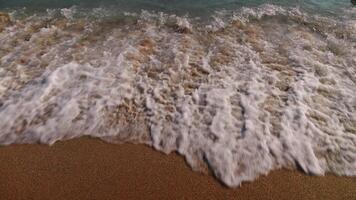 Sea waves with foam on the sandy shore of the beach. An idealistic picture on the shore of a warm sea. Calm video