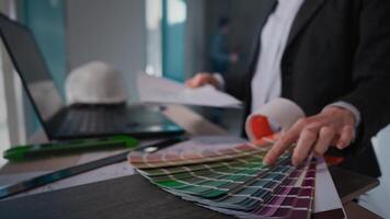 A man in a suit is seated at a desk holding a paint palette video