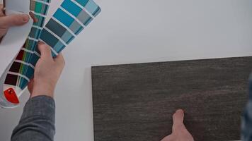 The architect, with the help of a construction engineer, selects materials for finishing the apartments. A man uses a professional palette to select the color of the walls video