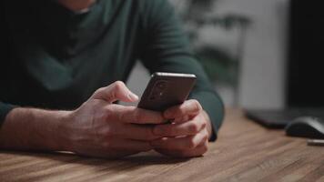 In the frame are male hands holding a modern smartphone. An unrecognizable man is using mobile internet to access applications on the smartphone. Modern devices at home video