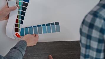 Two individuals are admiring a color palette displayed on the wall. Two people admiring a Tartan color palette on wall video