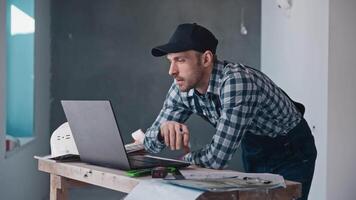 A man is standing at a desk with a laptop computer video