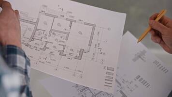 An engineer and a builder discuss a house project based on detailed drawings. Work on a construction site. Developer video