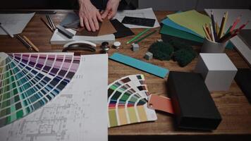 An unrecognizable female architect works in a design studio, developing interior styles. The woman uses material and texture samples, as well as color palettes and furniture, to select color schemes. video