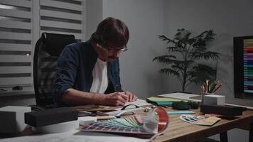 A male interior designer works with material samples, textures, color palettes, and drawings. An architect in the design studio develops an interior project, curating a mood board. video