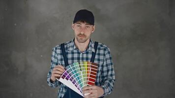 A male builder holds a palette in his hands to choose the color of the wall in an apartment under construction. Work on the interior video