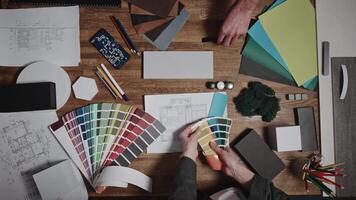 Working in a design studio. Interior designers are working with various palettes, textures, and material samples to select combinations for their project. The view is from above video