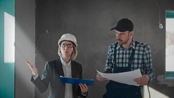A man in a suit and tie and a woman sharing a blueprint at a building event video