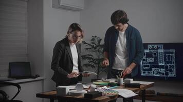 Design and architecture studio. A man and a woman are designers working with samples of materials and color palettes. Working on an apartment project. Laptop in frame video
