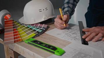 Man at table with ruler and pencil in hand, showing gesture of engineering video