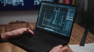 An architect is working on blueprints using a laptop. The shot shows male hands and a laptop with an engineering software program open. The project involves developing a construction plan video