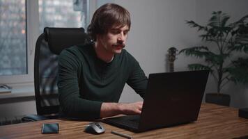 Man seated at table, using laptop computer in office setting video