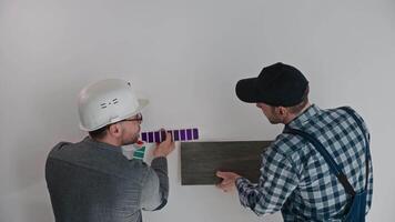 The architect, with the help of a construction engineer, selects materials for finishing the apartments. A man uses a professional palette to select the color of the walls. video