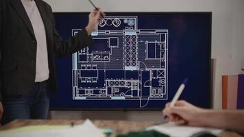 An unrecognizable woman makes a presentation of an architectural project in a design studio. House layout on the big screen video