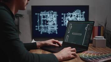 The shows male hands working with a laptop. An architect is drawing a room project using CAD software. An unidentified male engineer is working in an architectural studio video