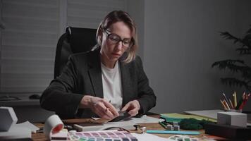 A stylish female architect works in a design studio, developing interior styles. The woman uses material and texture samples, as well as color palettes and furniture, to select color schemes. video