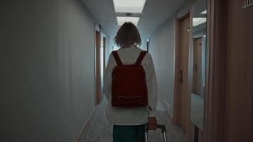 A young woman with a backpack and suitcase, checking into a hotel room. A traveler uses hotel rooms for overnight stays. Hospitality video