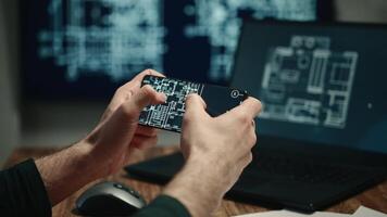 The shows male hands holding a smartphone and working on a laptop with building plans or blueprints displayed on the screens. The architect is working on a project. video
