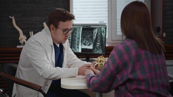 An osteopathic doctor consults a young woman. A man analyzes an MRI image to make a diagnosis for a patient. Reception after injury video