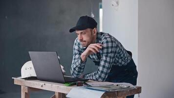 A construction engineer at a construction site works with projects using a laptop and blueprints. A man is responsible for finishing works and architectural solutions. video
