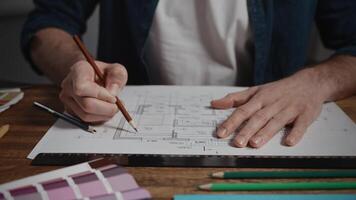 Unrecognizable male architect working with blueprint. The designer makes notes in the plan of the room. Working with architecture in a design office video