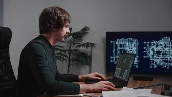 A man is seated at a desk using a laptop computer as an output device video
