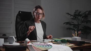 A stylish female architect works in a design studio, developing interior styles. The woman uses material and texture samples, as well as color palettes and furniture, to select color schemes. video